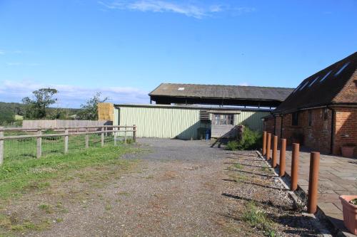a farm with a fence and a building at Parkfields Barns Self Catering Accommodation in Buckingham