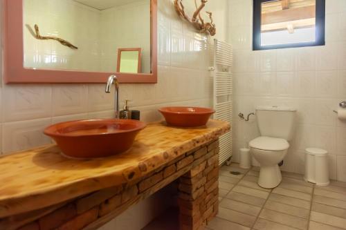 a bathroom with two copper sinks and a toilet at AMNISIADES APARTMENTS in Karteros