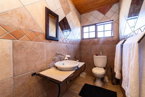 a bathroom with a sink and a toilet at Thatch Haven Guesthouse in Centurion