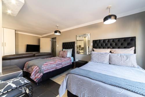 a bedroom with two beds and a couch at Thatch Haven Guesthouse in Centurion