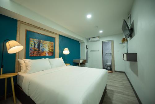 a bedroom with a large white bed and a blue wall at SkyLink Homes in Bangkok