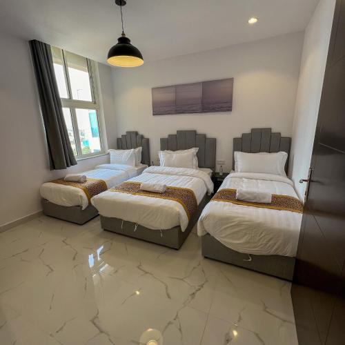 a bedroom with three beds and a large window at The Red Sea Apartment شقة البحر الأحمر in Jeddah