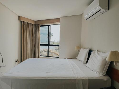 a bedroom with a large white bed with a window at Conforto e Vista Maravilhosa no Hotel Iate Plaza in Fortaleza