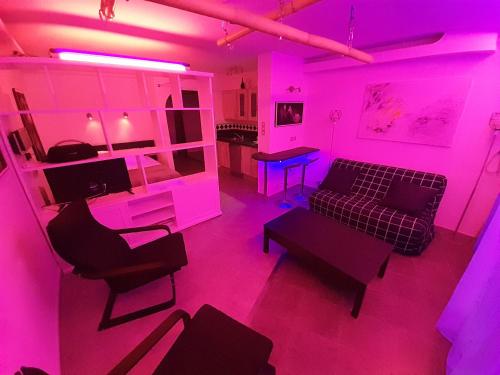 - un salon avec un éclairage rose et un canapé dans l'établissement Appartement Village Naturiste Shibari, au Cap d'Agde