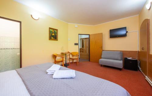 a bedroom with a bed and a chair and a television at Penzión Max Kežmarok in Kežmarok