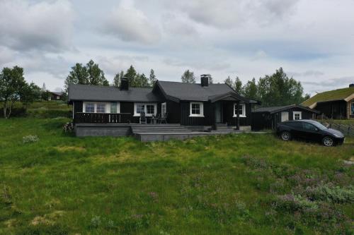 a house with a car parked in a field at Cozy, well-equipped and family-friendly cabin in Geilo in Geilo