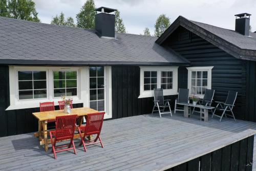 a deck with red chairs and a wooden table at Cozy, well-equipped and family-friendly cabin in Geilo in Geilo