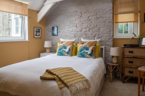 a bedroom with a large white bed with a stone wall at Zen Den Cornwall in Boscastle
