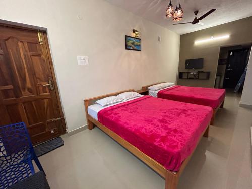 two beds in a room with red sheets at Aarudra's Residency Srirangam in Tiruchchirāppalli
