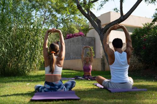 a group of people doing yoga in the grass at Can Lluc Boutique Country Hotel & Villas, a member of Beyond Green in Sant Rafael de Sa Creu