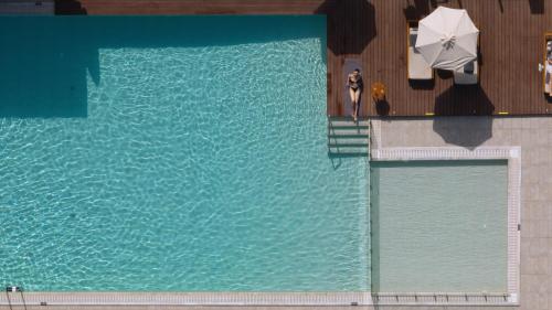 an overhead view of a swimming pool with a man standing next to an umbrella at Asterion Suites & Spa - Designed for Adults in Gerani Chanion