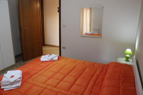 a bedroom with a large orange bed with towels on it at Casa P&G in Niscemi