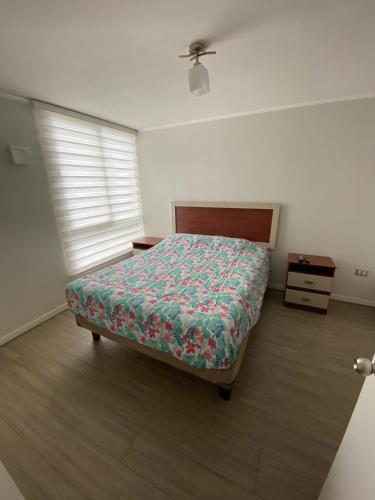 a bedroom with a bed and a dresser and a window at DEPARTAMENTO EL OASIS in La Serena