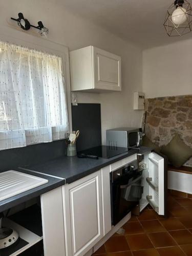 une cuisine avec des armoires blanches et un comptoir noir dans l'établissement Ancienne petite bastide provençale, à Sanary-sur-Mer