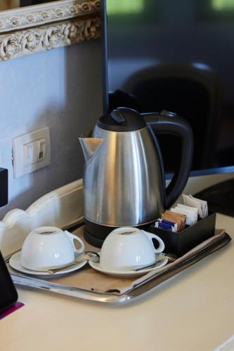 a tea kettle and two saucers on a tray at Hotel Borgo Di Cortefreda - Place of Charme in Tavarnelle in Val di Pesa