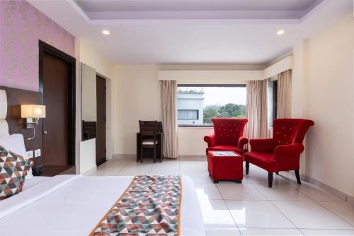 a bedroom with red chairs and a bed and a window at Indira Nikunj Rubystone Exotic in Rishīkesh