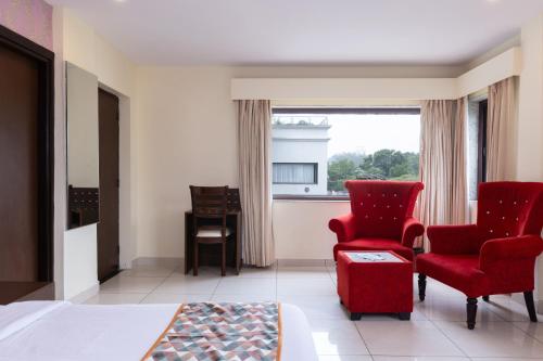 a bedroom with red chairs and a bed and a window at Indira Nikunj Rubystone Exotic in Rishīkesh