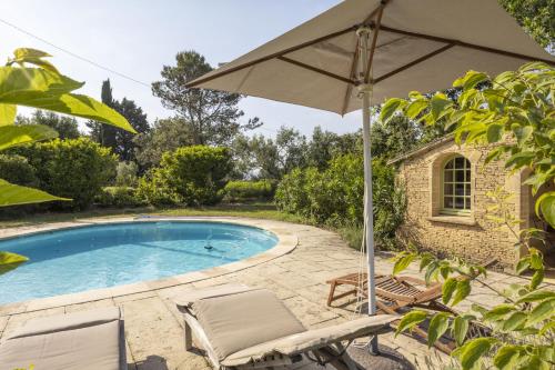 un parasol et des chaises à côté d'une piscine dans l'établissement Les Oliviers, à Saint-Maximin