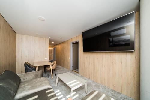 a living room with a couch and a television on a wall at Zaliakalnio Terasos apartamentai 2 in Kaunas