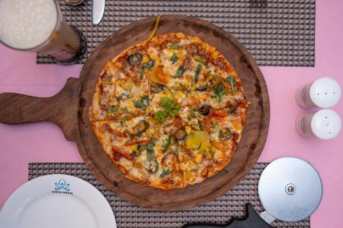 a pizza on a wooden board on a table at Indira Nikunj Rubystone Exotic in Rishīkesh
