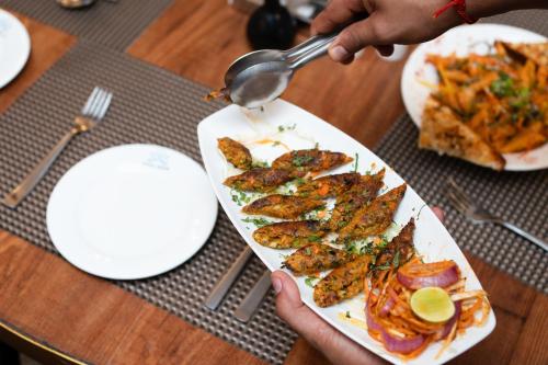 a person holding a plate of food on a table at Indira Nikunj Rubystone Exotic in Rishīkesh