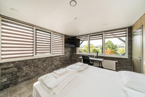 a bedroom with two beds and a desk and windows at Zaliakalnio Terasos apartamentai 2 in Kaunas