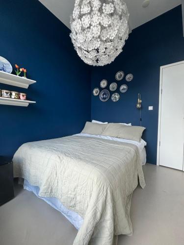 アムステルダムにあるLovely small apartment in 'De Pijp'の青いベッドルーム(ベッド1台、シャンデリア付)