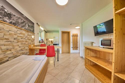 a living room with a television and a table with red chairs at Ski & Bike Appartements Forsthaus in Saalbach Hinterglemm