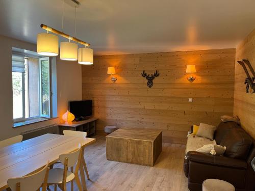 a living room with a table and a couch at Loft 5 personnes type chalet avec jardin in Saint-Maurice-sur-Moselle