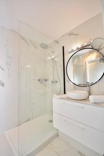 La salle de bains blanche est pourvue d'une douche et d'un miroir. dans l'établissement Studio Trocadero - Sablons, à Paris