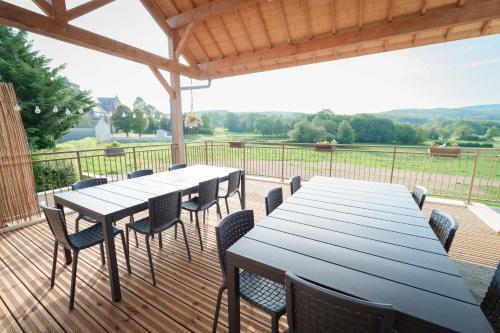 a large wooden deck with tables and chairs on it at Gîte du Haut Morvan in Arleuf