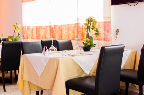 a table with black chairs and a yellow table cloth at Bano Palace Hotel in Douala
