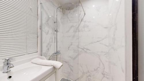 une salle de bain blanche avec une douche et un lavabo dans l'établissement Bluestay 114 : Superbe appartement à Bastille, à Paris