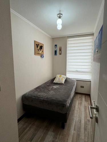 a bedroom with a bed in a room with a window at Apartamento Centro de Concepcion in Concepción