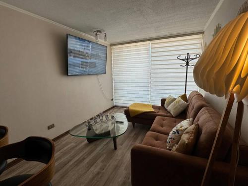 un soggiorno con un divano e un tavolo di vetro di Apartamento Centro de Concepcion a Concepción