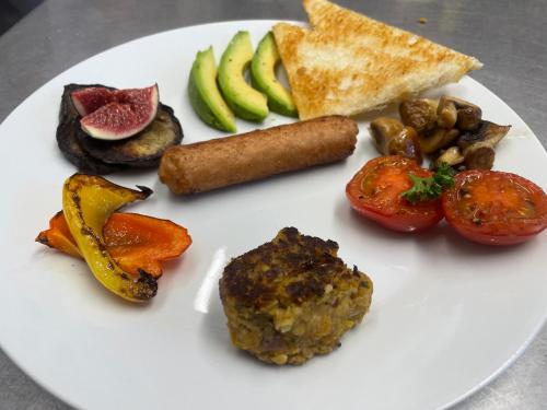a white plate of food with vegetables and bread at Cnapan Guest House in Newport Pembrokeshire