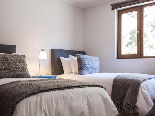 two beds in a white room with a window at NOI Puma Lodge in Machalí