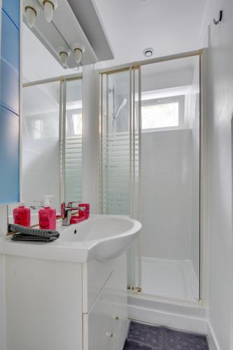 une salle de bain blanche avec un lavabo et une douche dans l'établissement Studio chic aux portes de Paris, à Colombes