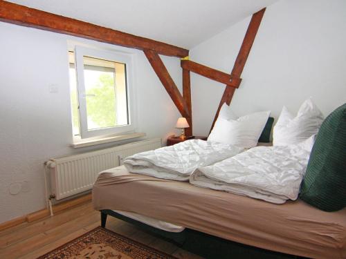 Un dormitorio con una cama con sábanas blancas y una ventana. en Behagliche Ferienwohnung im idyllischen Körchow, en Körchow