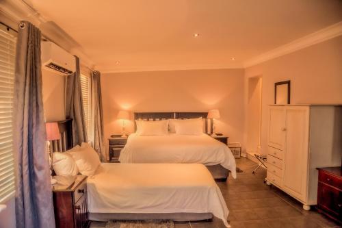 a bedroom with two beds with white sheets at Nauntons Guest House & Wedding Venue in Ladysmith