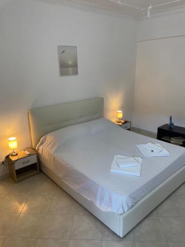 a white bed in a room with two lamps at Happy house in Civitavecchia