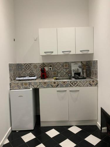 - une cuisine avec des placards blancs et un sol en damier dans l'établissement Maison colonnes 4 personnes, à Bastia