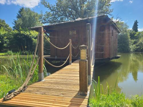 a wooden dock with a boat house on the water at Le Domaine de la Vergnolle in Roches