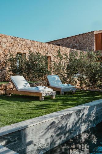 - deux lits assis sur l'herbe à côté d'une piscine dans l'établissement Appartement premium de 70m2 avec piscine individuelle, à Grosseto-Prugna