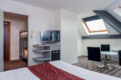a bedroom with a bed and a tv and a table at Brit Hotel Belfort Centre-Le Boreal in Belfort