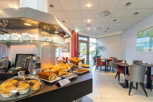 a buffet line with bread and pastries in a restaurant at Brit Hotel Belfort Centre-Le Boreal in Belfort