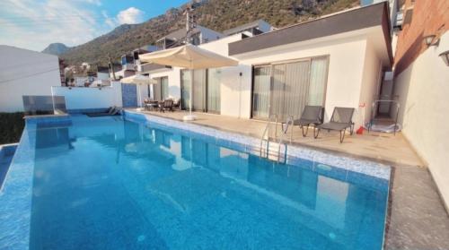 ein großer Swimmingpool mit Stühlen und einem Haus in der Unterkunft Ada Villa in Kalkan
