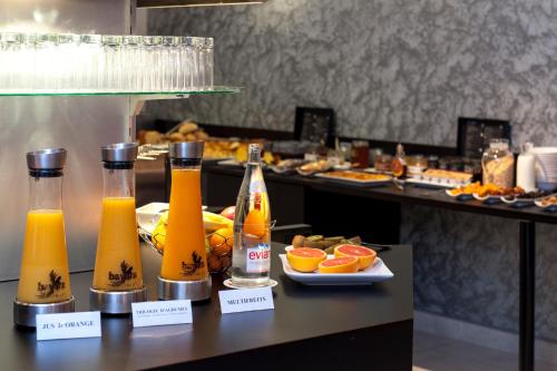 a buffet line with bottles of orange juice and fruits at Brit Hotel Belfort Centre-Le Boreal in Belfort