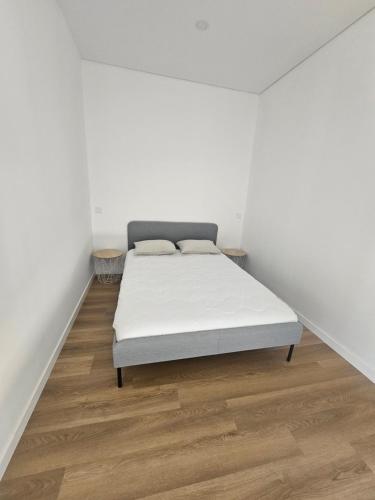 ein Bett in einem Zimmer mit weißen Wänden und Holzböden in der Unterkunft Casa da leira in Madalena