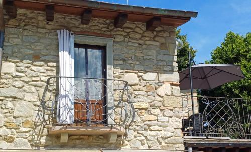 a stone building with a balcony with an umbrella at La Casetta di Noah in Pratovecchio